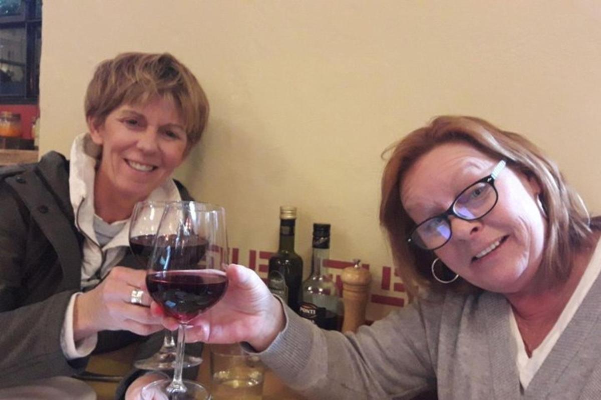 to kvinner som sitter ved et bord og holder et glass vin