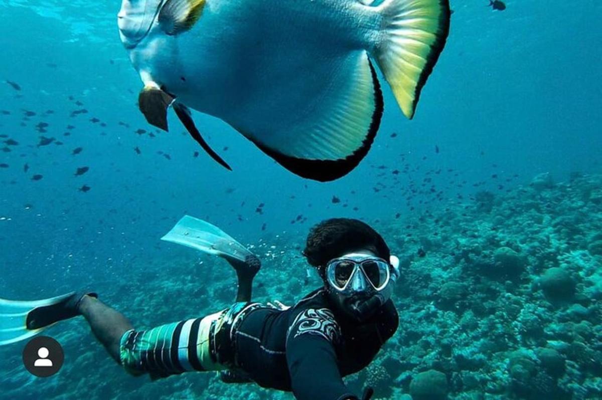 un uomo con boccaglio e un pesce nell'acqua