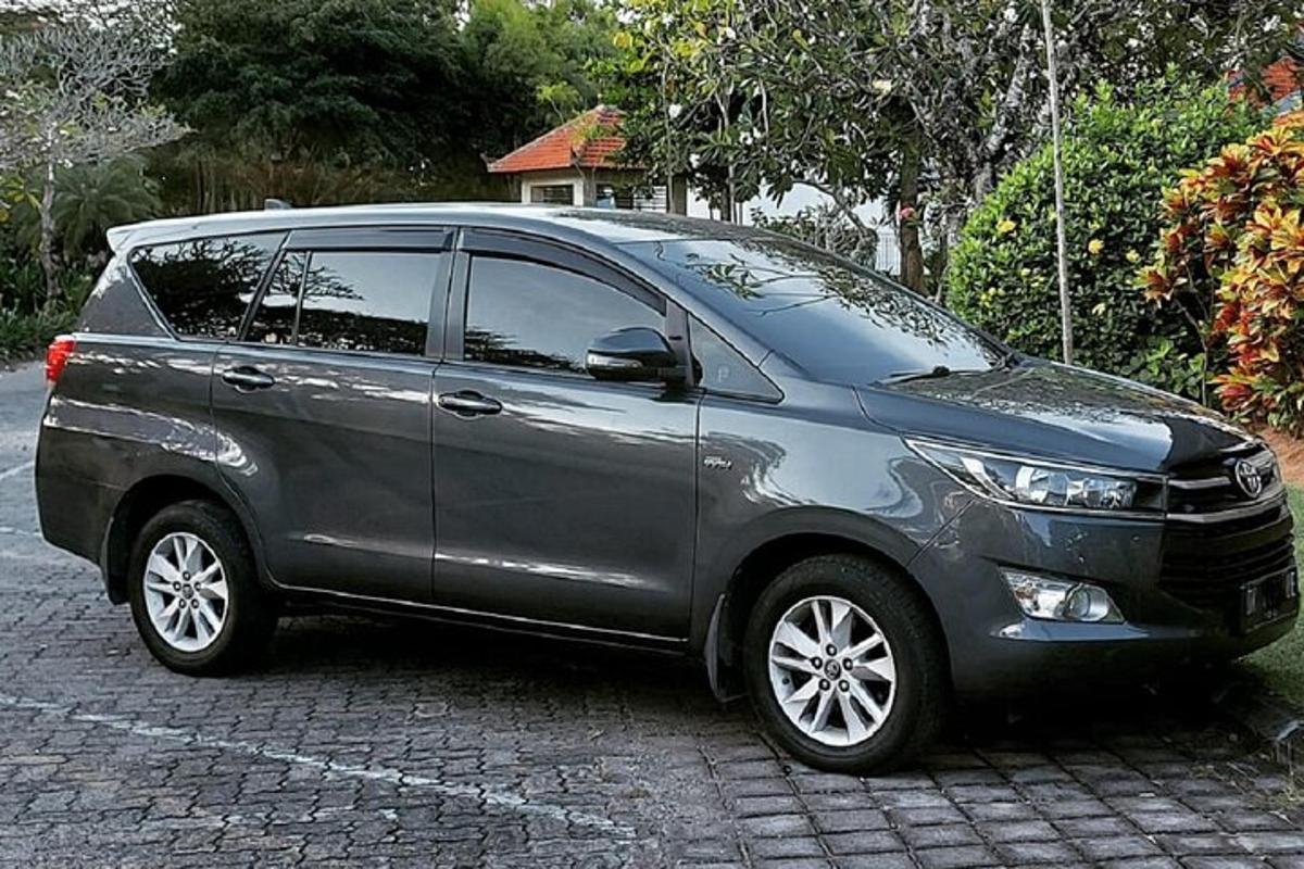 uma minivan prateada estacionada em uma rua de tijolos