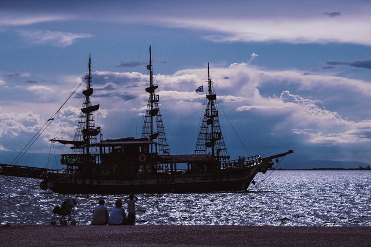 velik čoln v vodi z ljudmi, ki stojijo na plaži