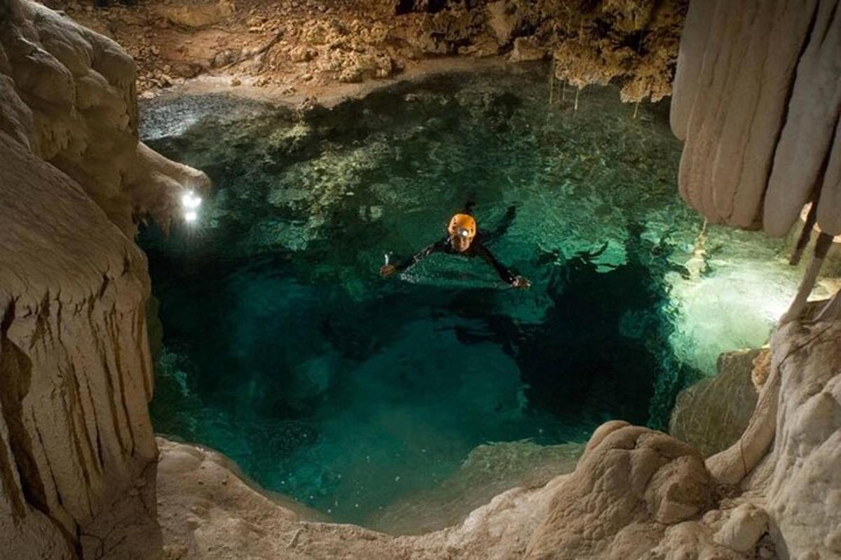 ein Mann, der in einem Wasserbecken in einer Höhle schwimmt