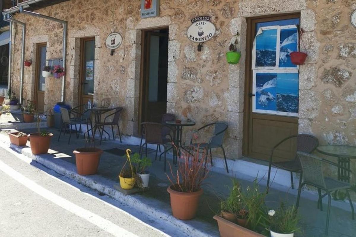 a restaurant with chairs and tables and plants in front of a building