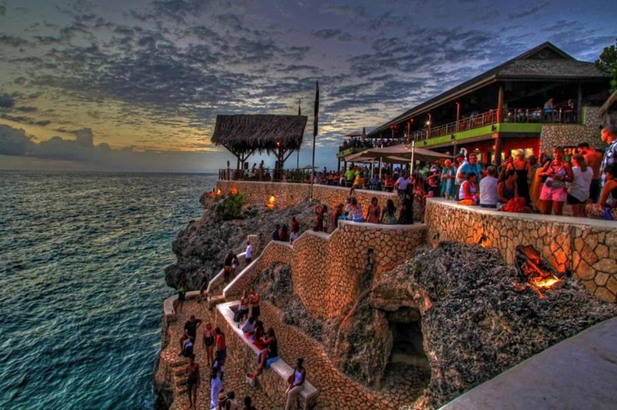 o mulțime de oameni care stăteau în jurul unui restaurant pe malul oceanului