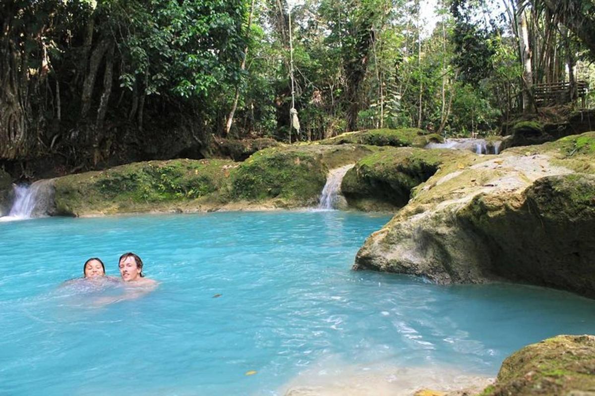 dua orang berenang di kolam air dengan air terjun