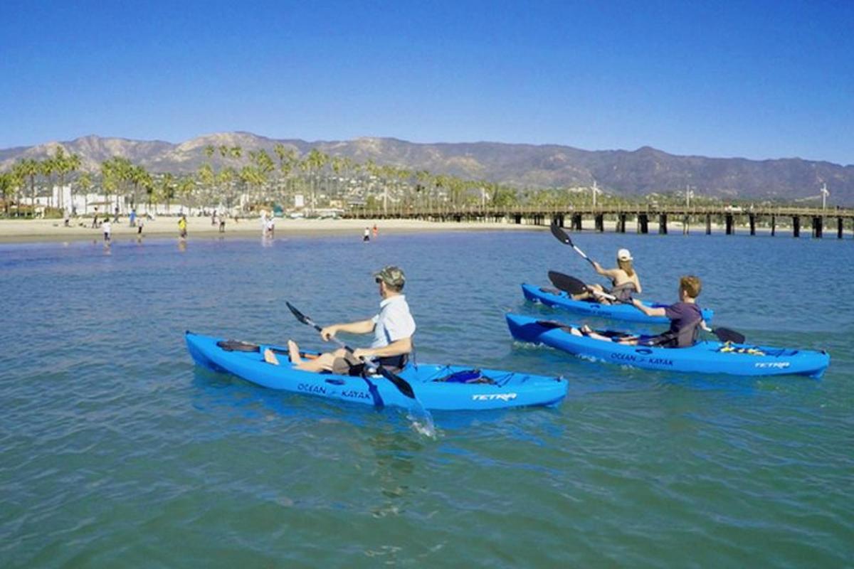 three people in kayaks in the water near a beach