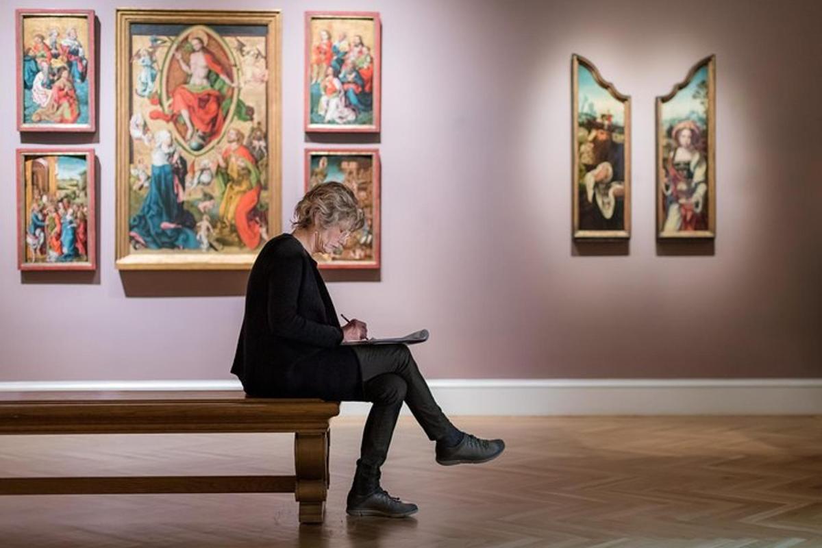 een vrouw zittend op een bankje in een kunsttentoonstelling