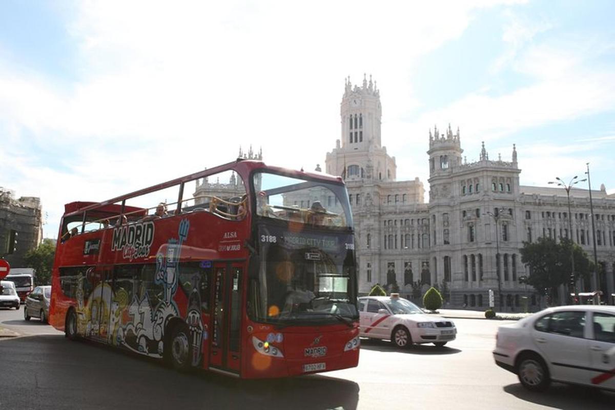 a red double decker bus driving in front of a building