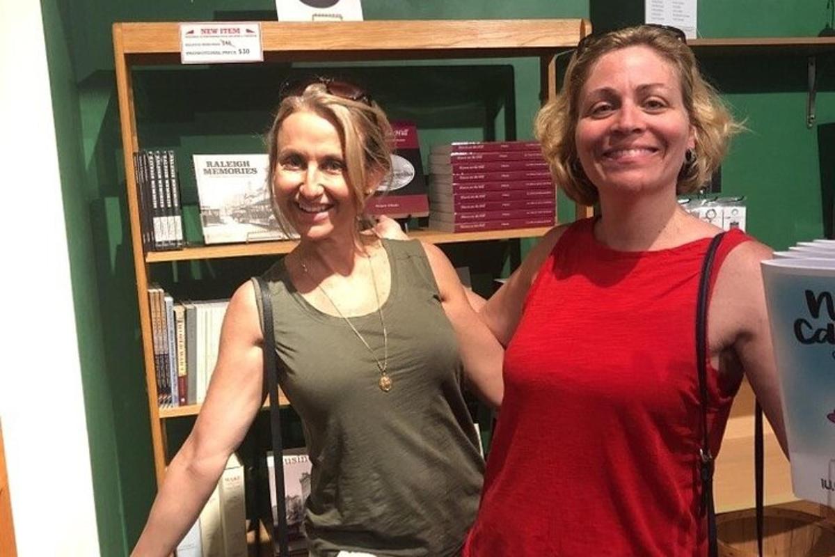two women standing in front of a book shelf