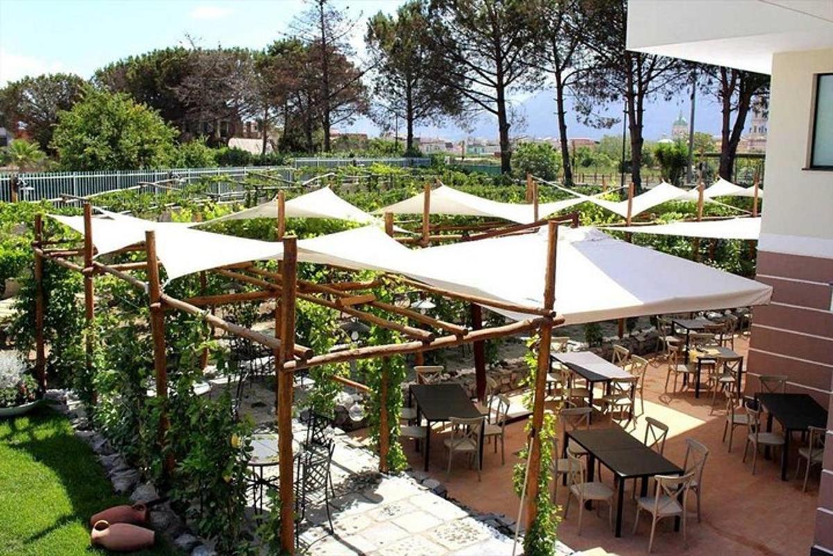 un patio con tavoli e ombrelloni bianchi in un giardino