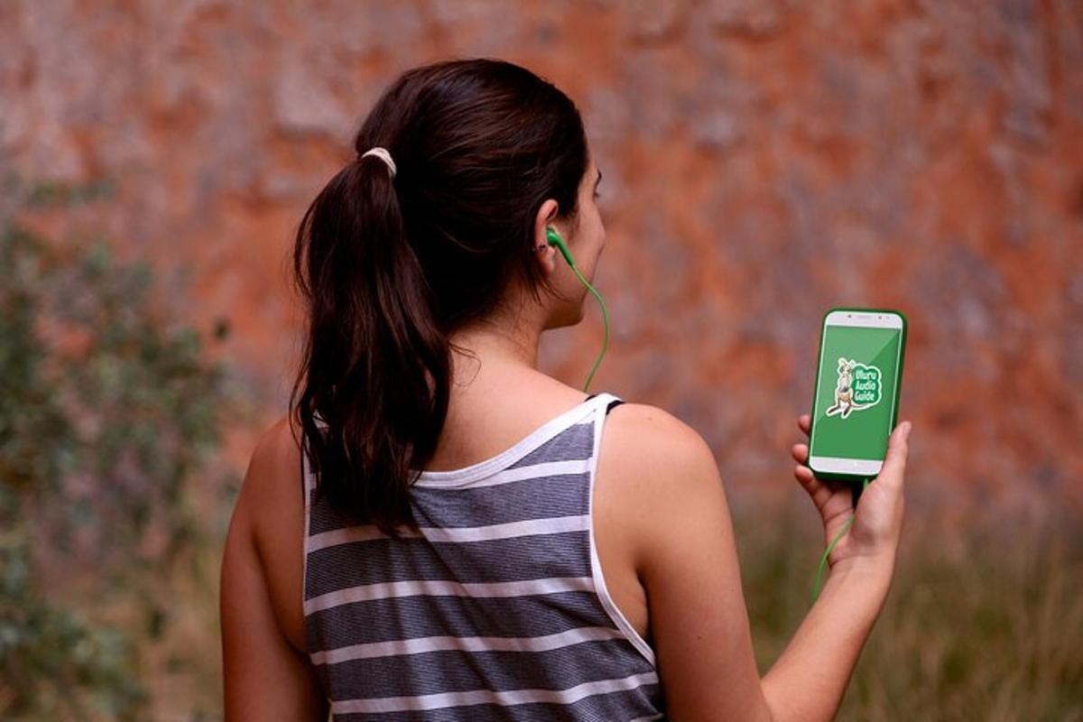 a woman wearing headphones holding a green cell phone