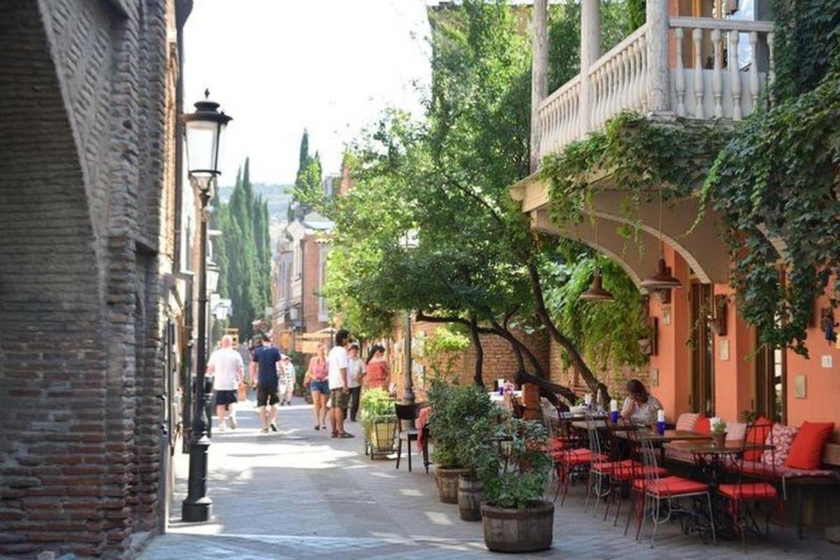 un gruppo di persone che camminano lungo una strada con tavoli e sedie