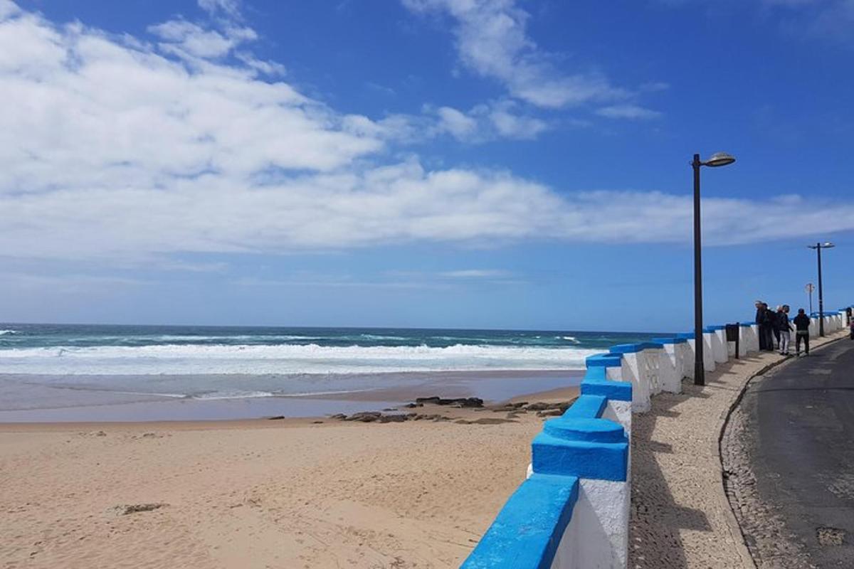 uma praia com uma cerca azul ao lado do oceano