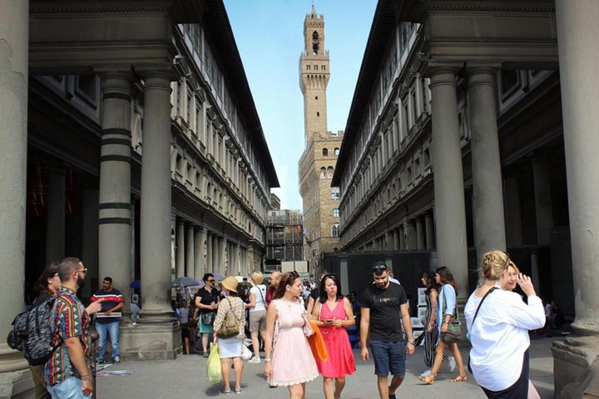 um grupo de pessoas caminhando por uma rua com uma torre do relógio