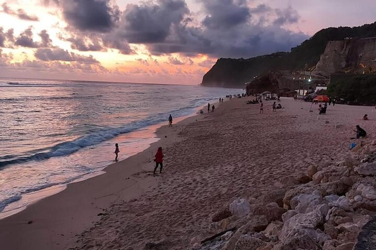 en gruppe mennesker på en strand ved solnedgang
