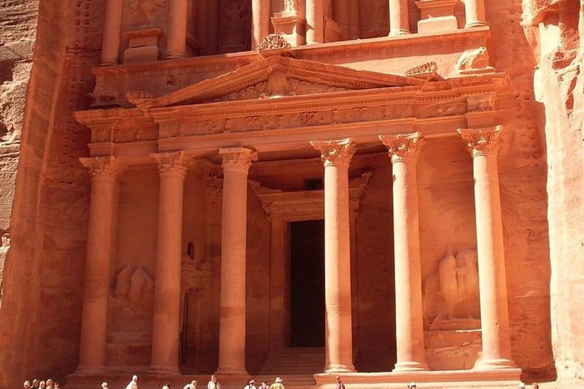 an ancient building with people standing in front of it