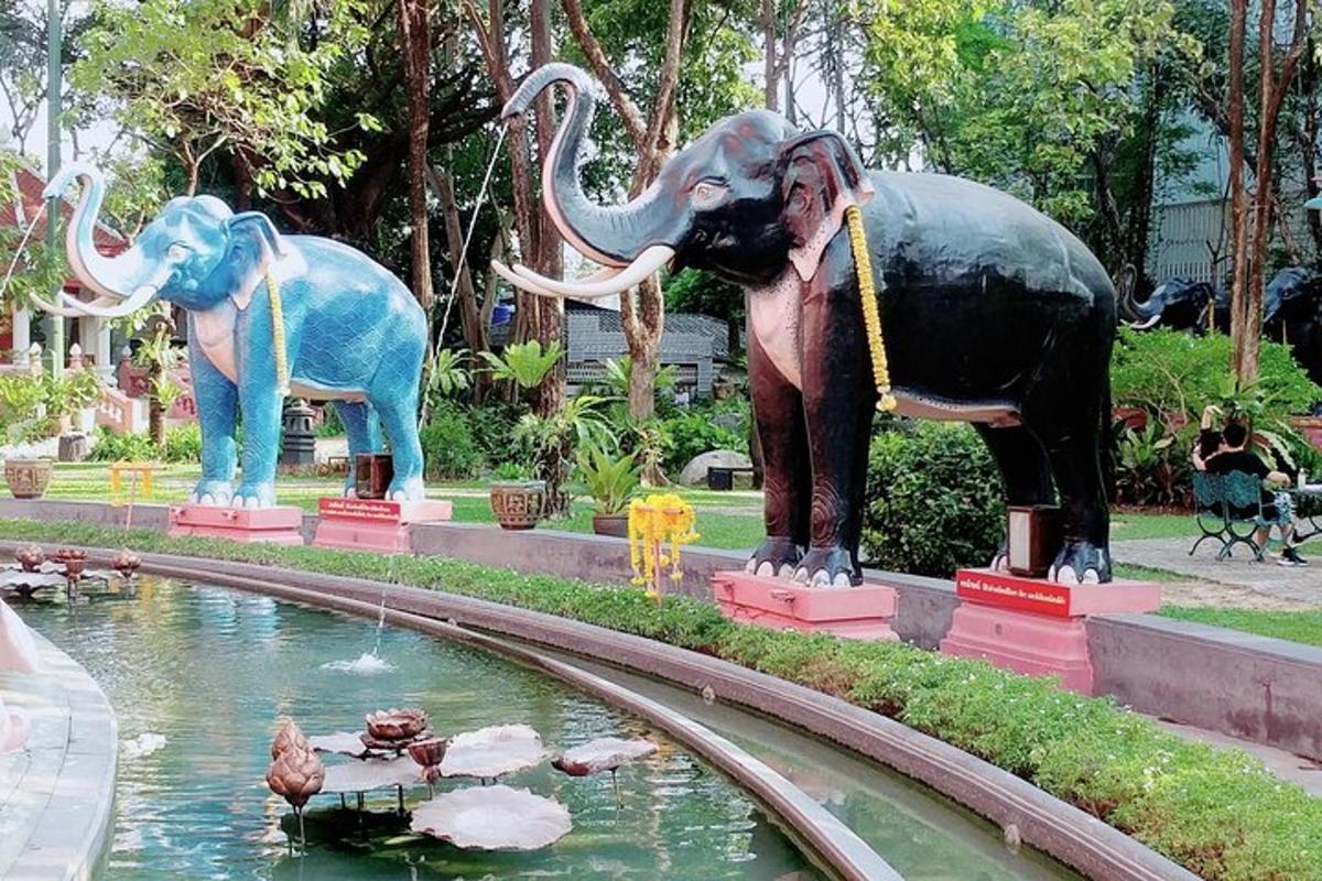 dua patung gajah berdiri di sebelah kolam