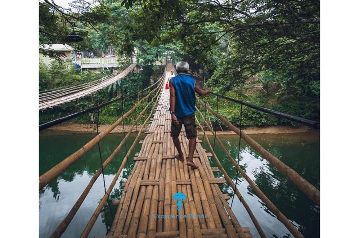 a man crossing a bamboo bridge over a river