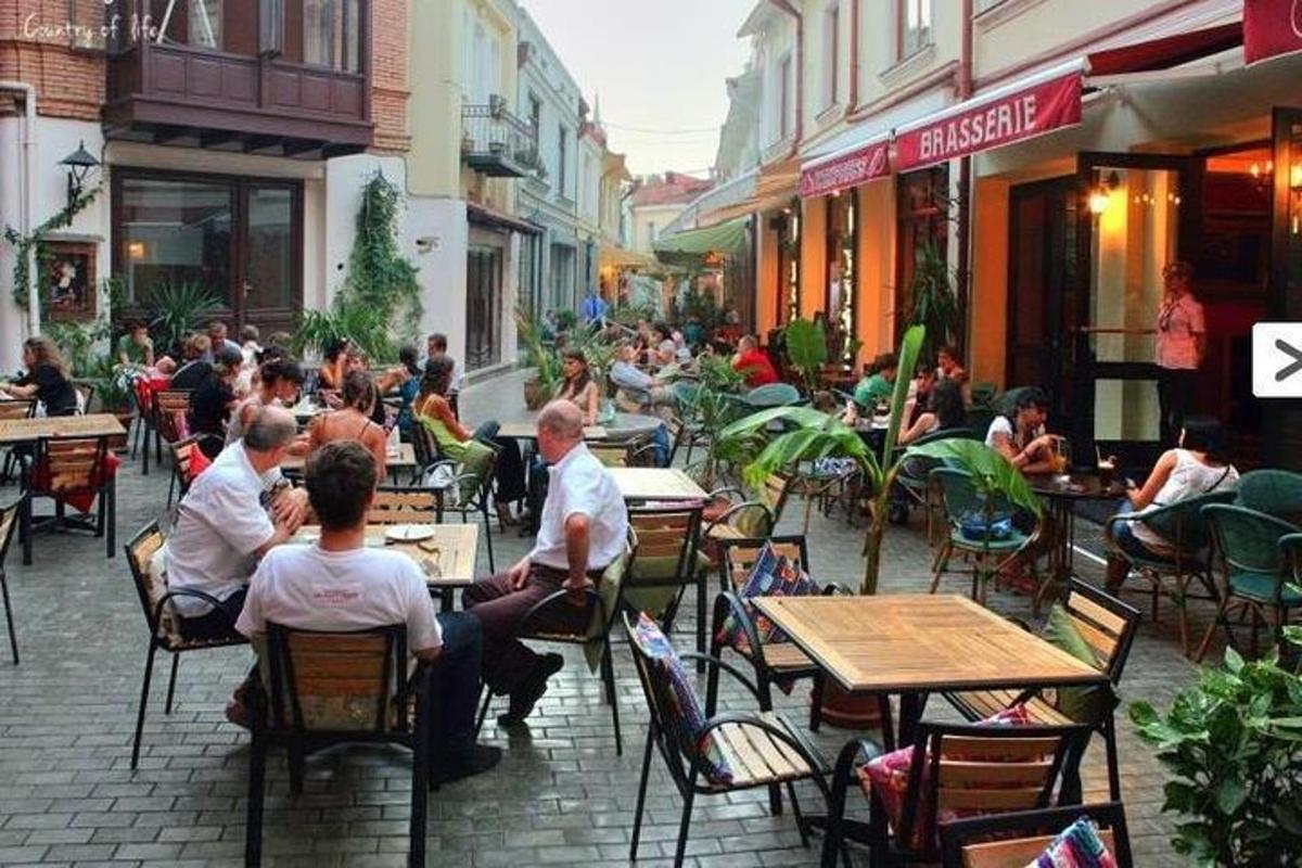 skupina ljudi, ki sedijo za mizami pred restavracijo