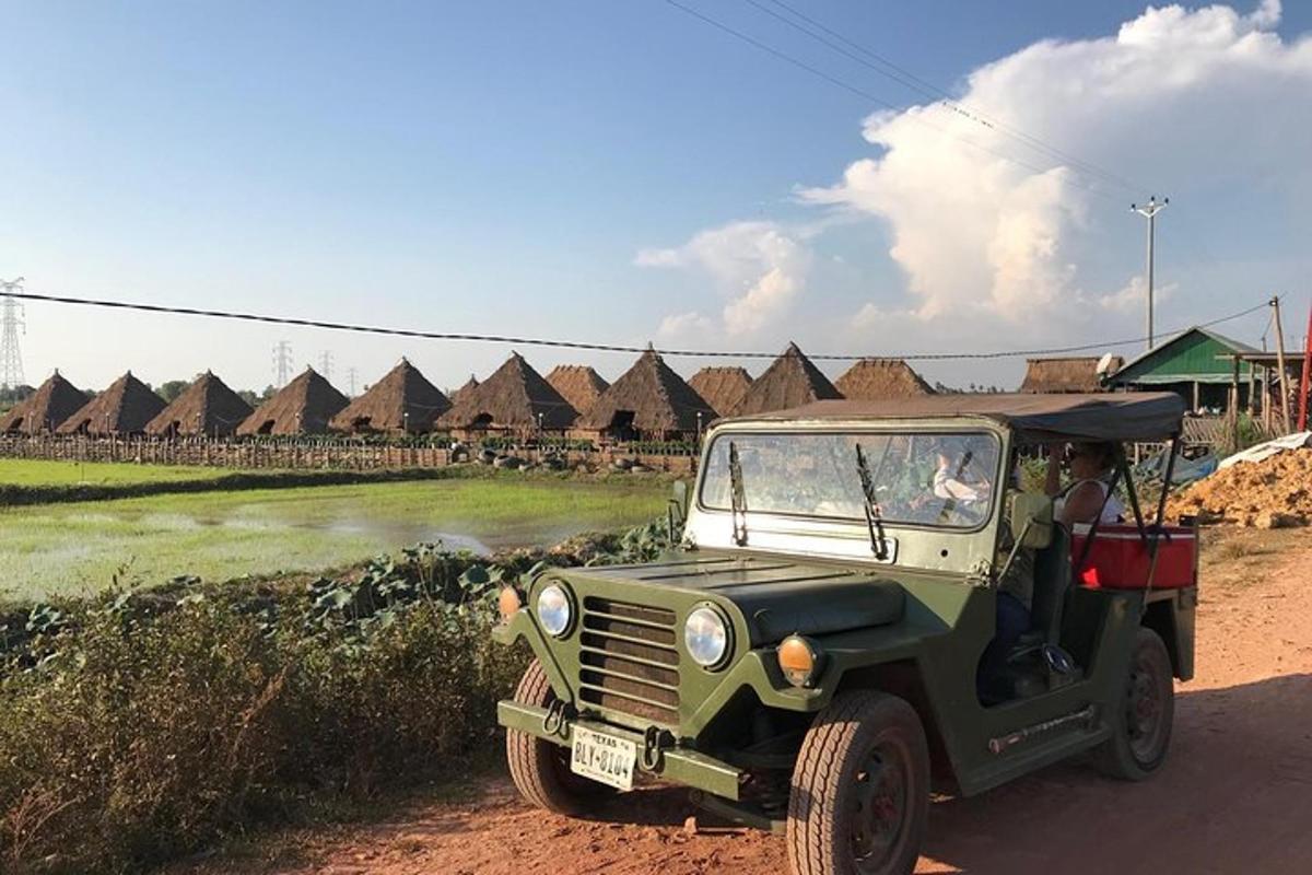 un jeep verd aparcat en un camí de terra al costat d'un camp