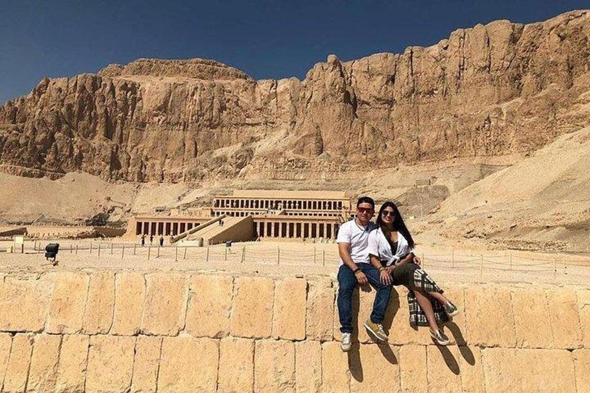 un uomo e una donna seduti su un muro di fronte a una montagna