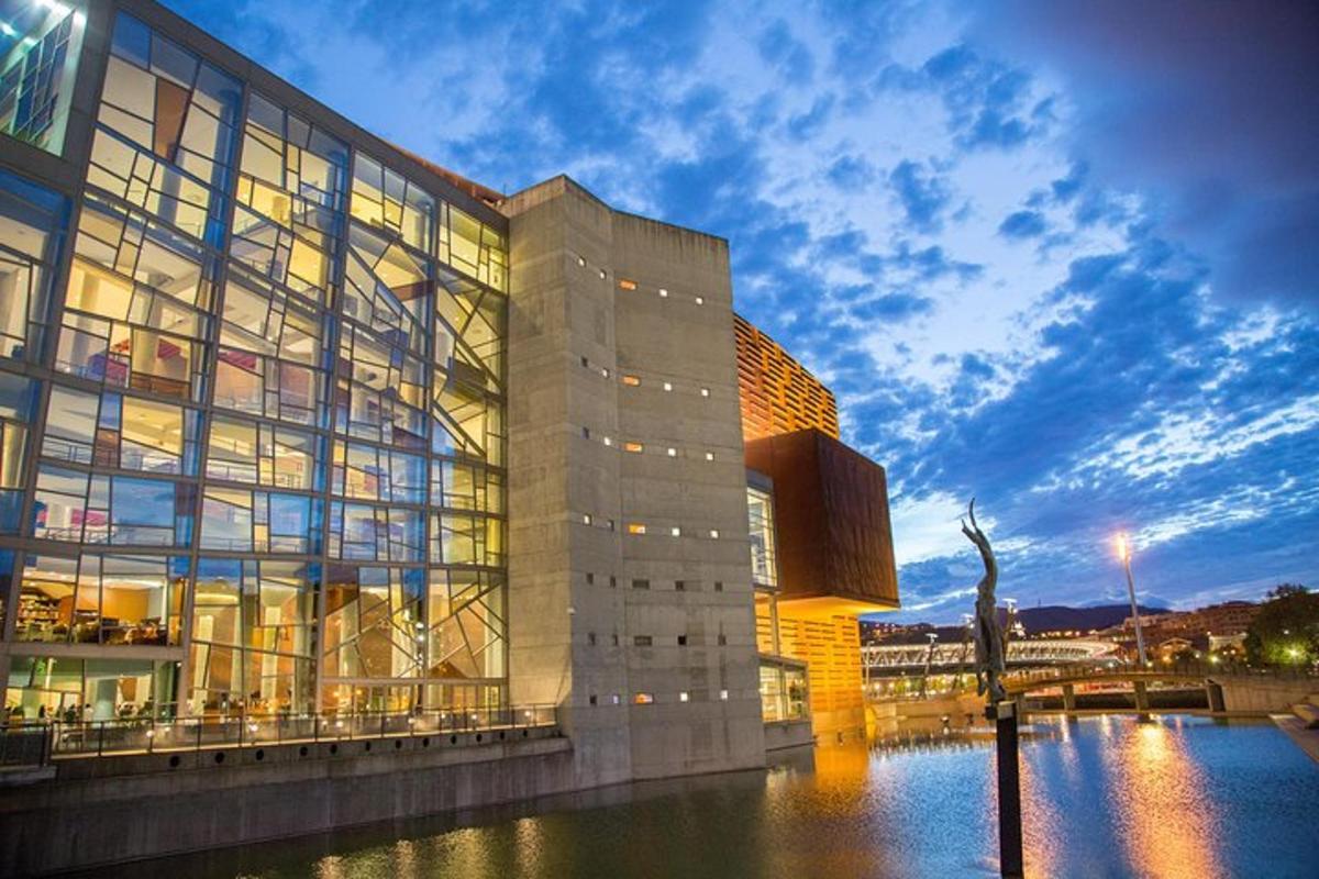 a large glass building with a river in front of it
