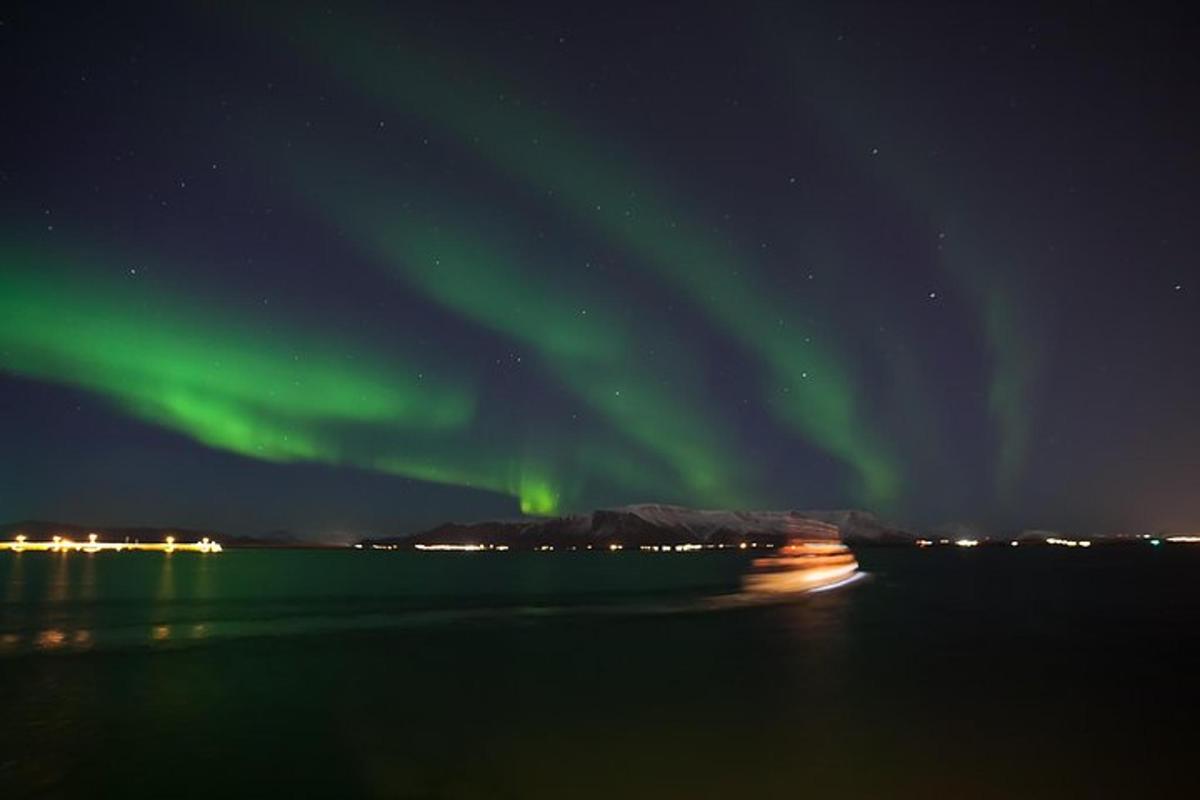 an aurora over the water with a boat in the ocean