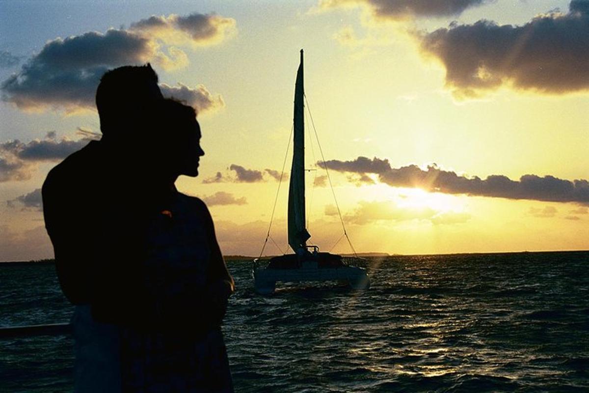 a man standing in front of a sail boat in the ocean