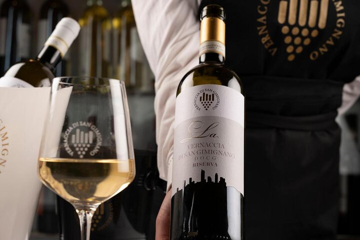 oseba, ki drži steklenico vina poleg kozarca
