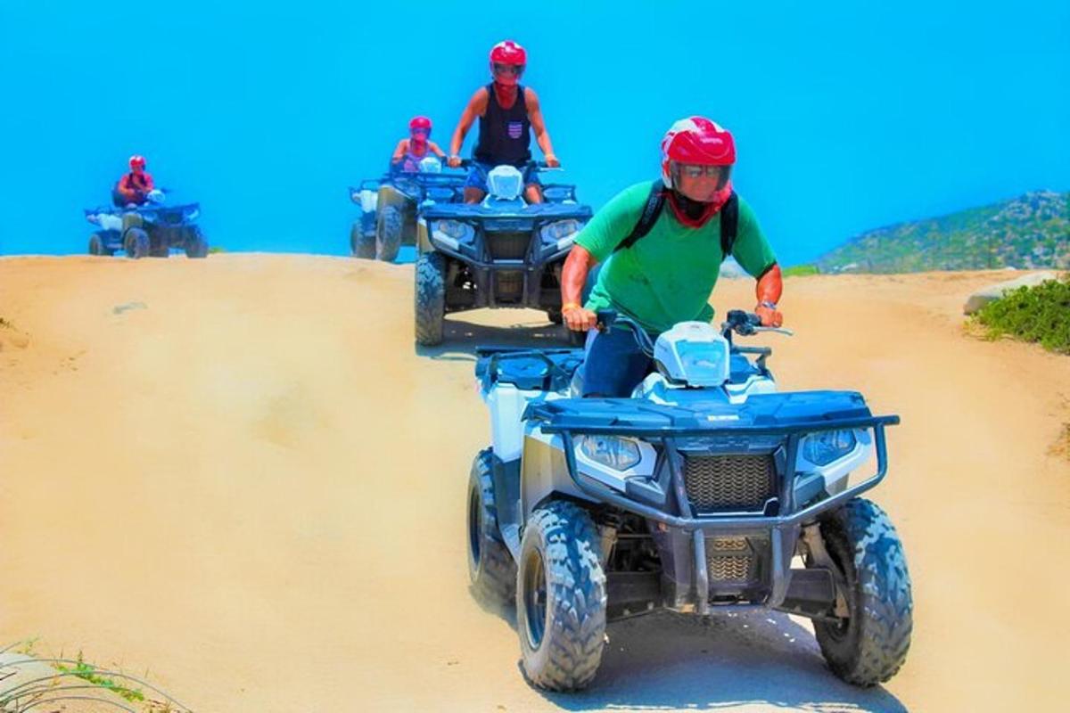 kolm inimest sõidavad ATV-dega liival