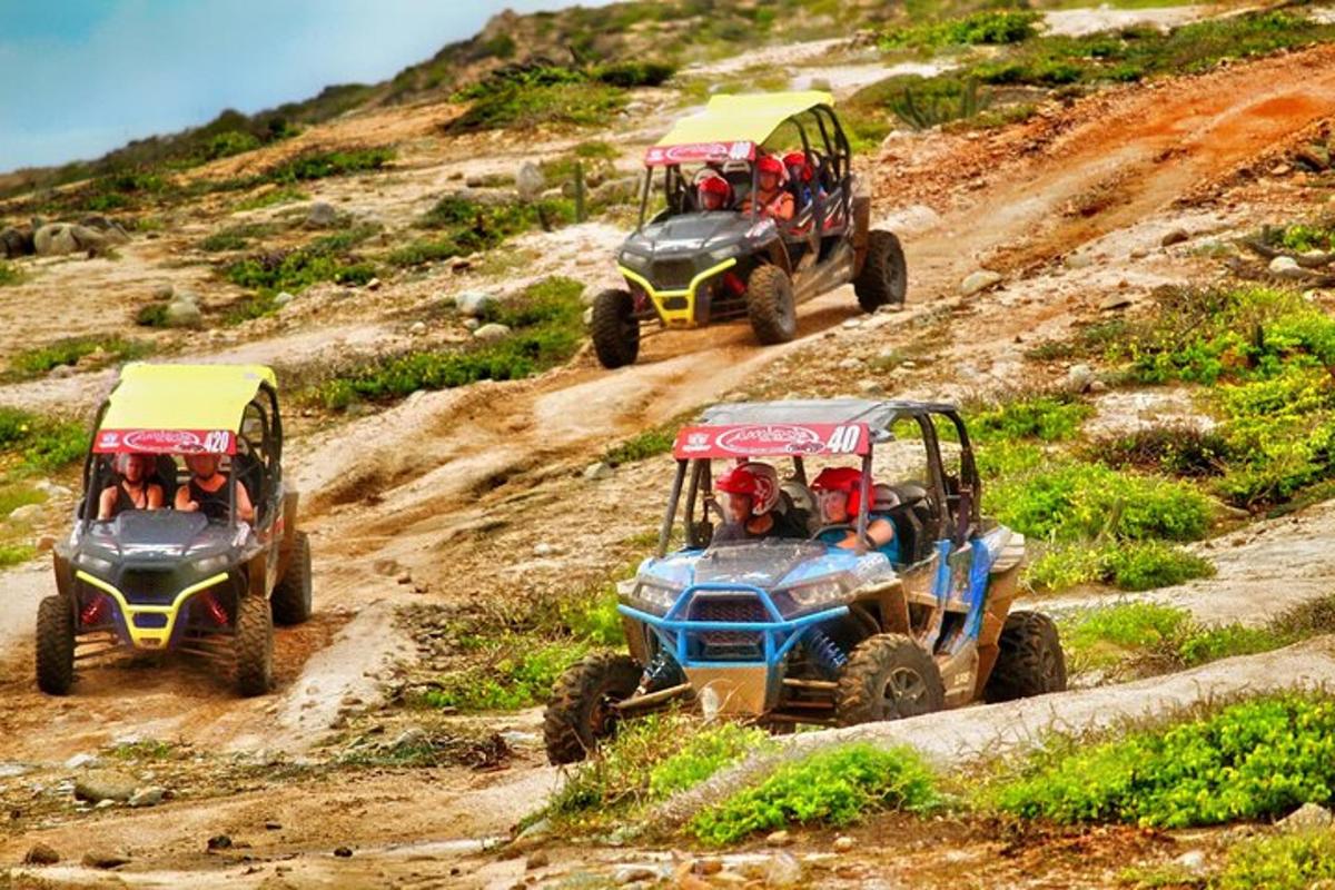 three atvs driving down a dirt hill with people