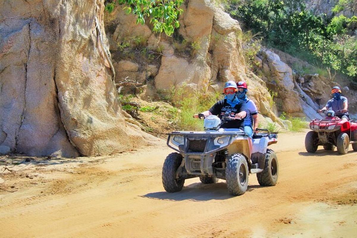 kolm inimest sõidavad ATV-dega kruusateel