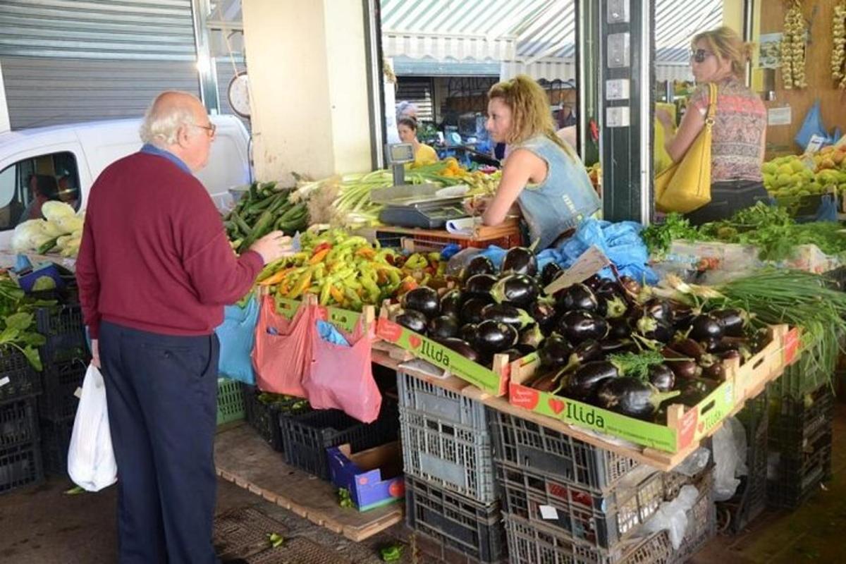 an older man standing in front of a produce stand at a market