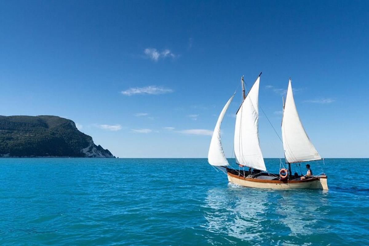 a sail boat with white sails in the ocean