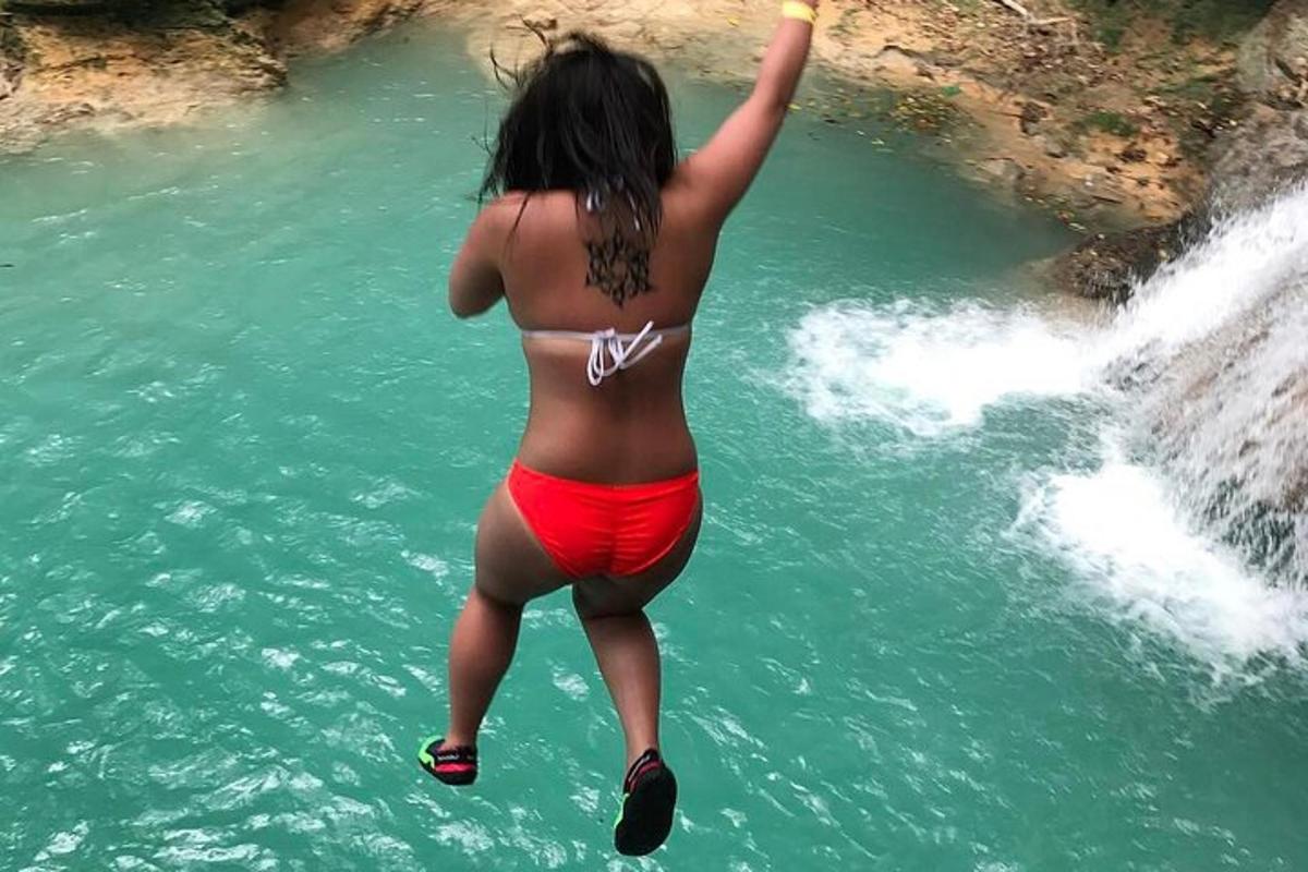 een vrouw in bikini die in een waterval springt