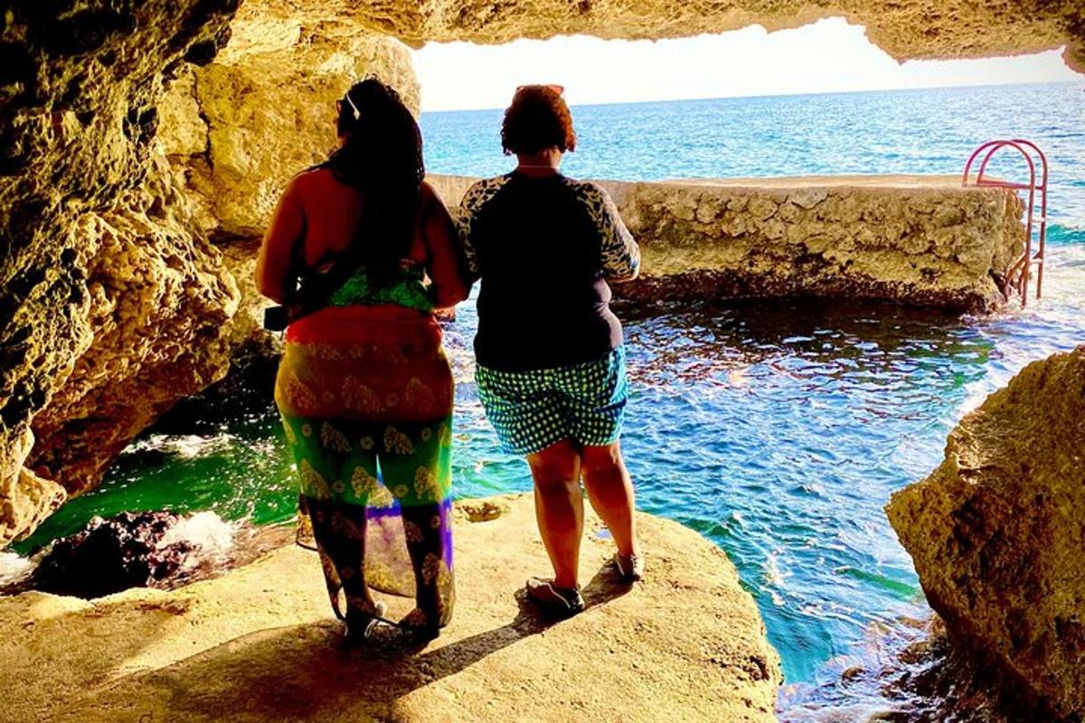 Dos mujeres caminando por una cueva hacia el océano.
