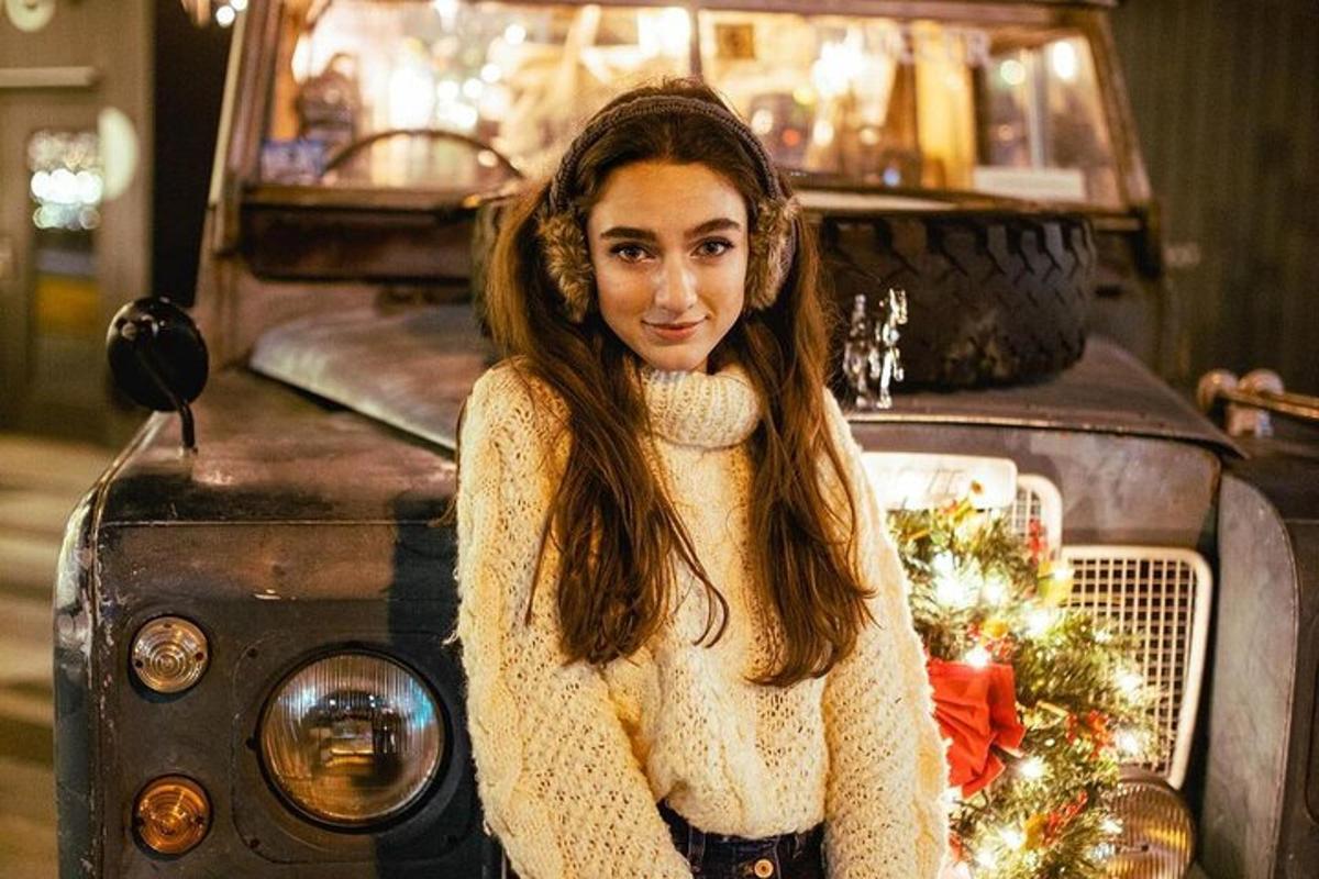 una donna in piedi sul davanti di una vecchia auto