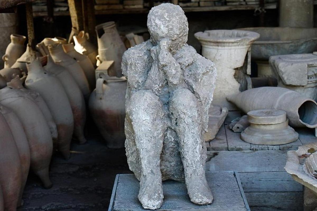 ένα άγαλμα ενός ατόμου που κάθεται μπροστά σε βάζα