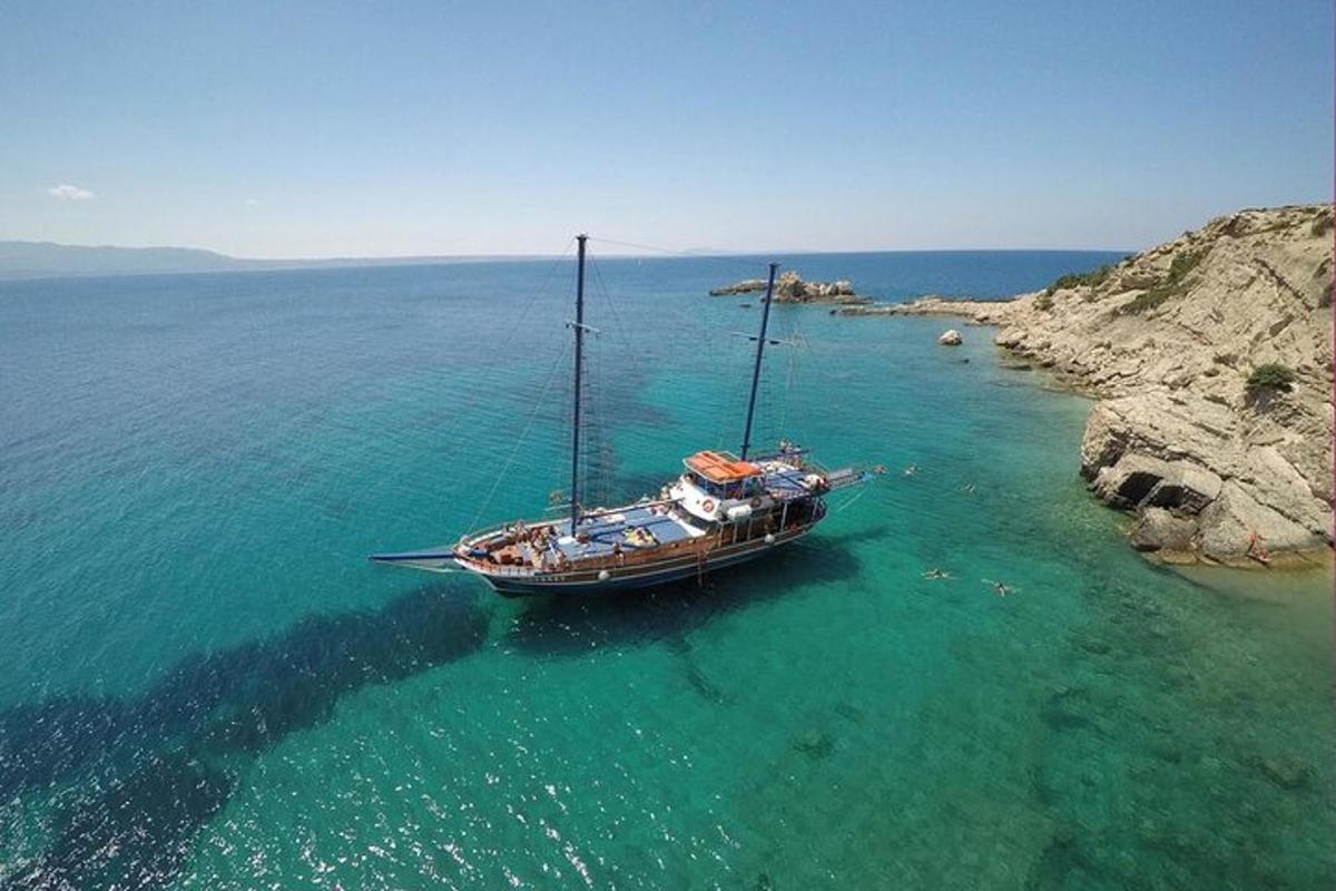 a boat sitting in the water next to a cliff