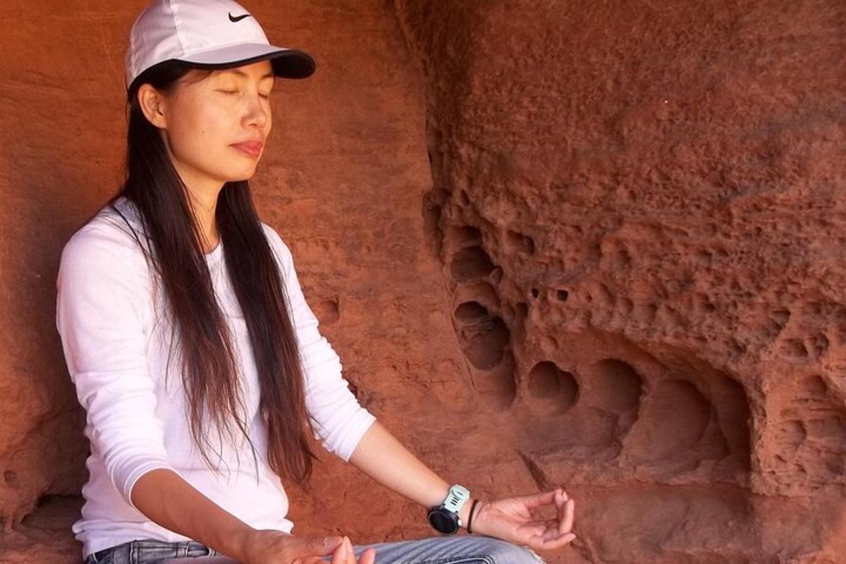 seorang wanita duduk dalam meditasi di hadapan formasi batu