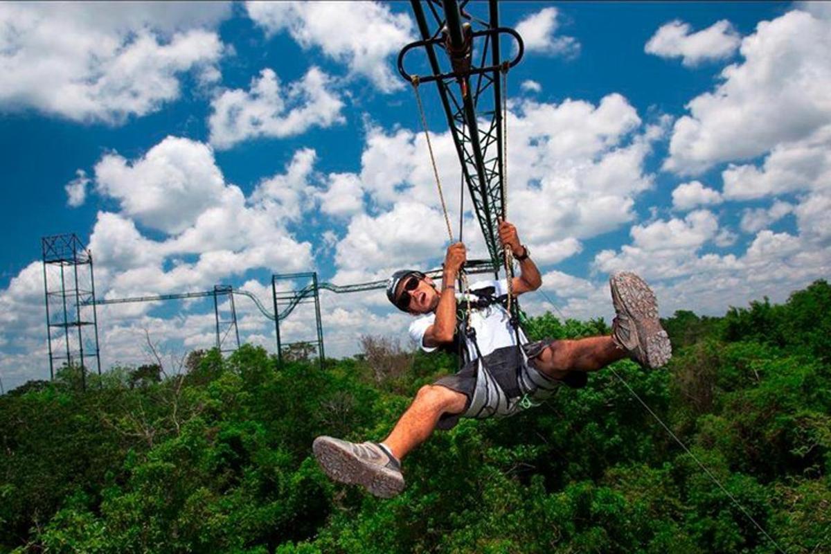 a man hanging from a rope on a zip line