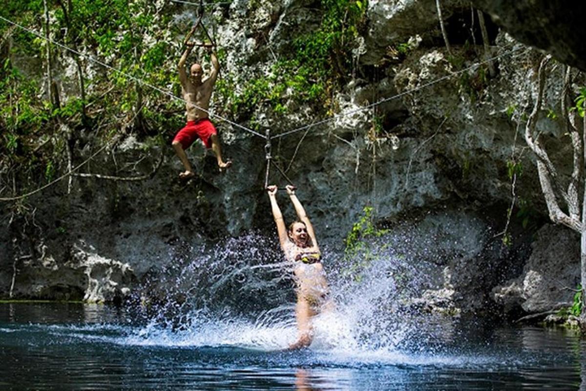 two people jumping off a rope in the water