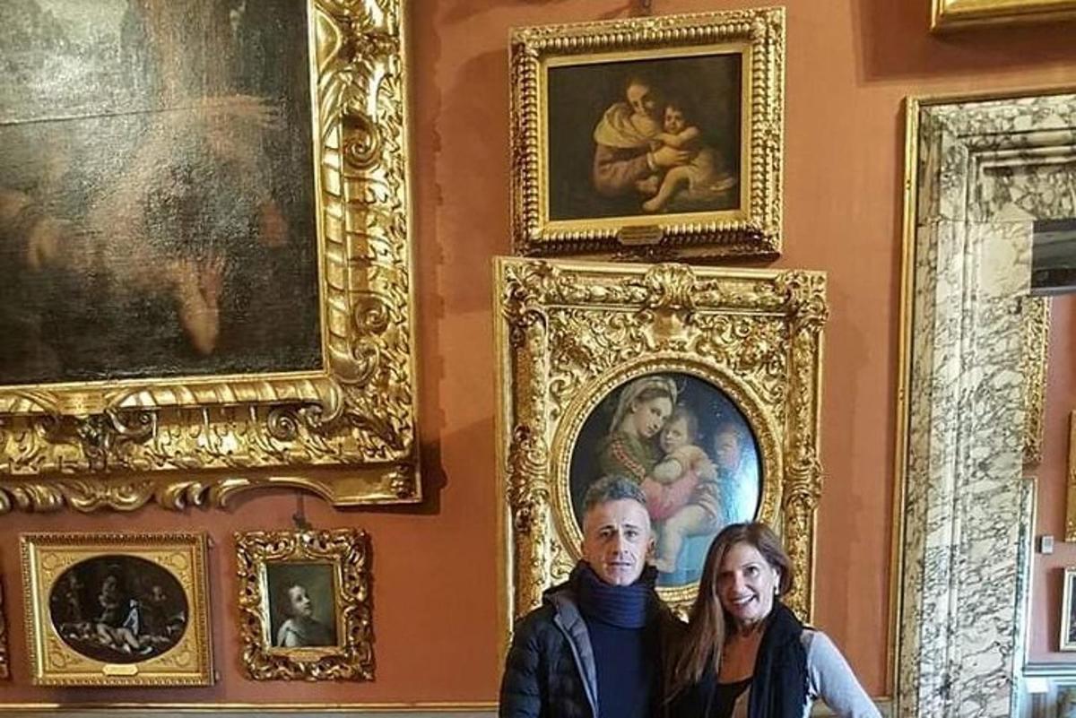 Ένας άντρας και μια γυναίκα στέκονται σε ένα δωμάτιο με πίνακες ζωγραφικής
