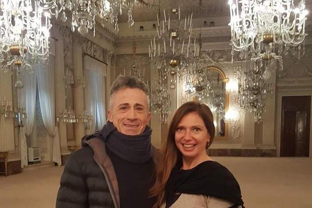 Ένας άντρας και μια γυναίκα ποζάρουν σε ένα δωμάτιο με πολυελαίους