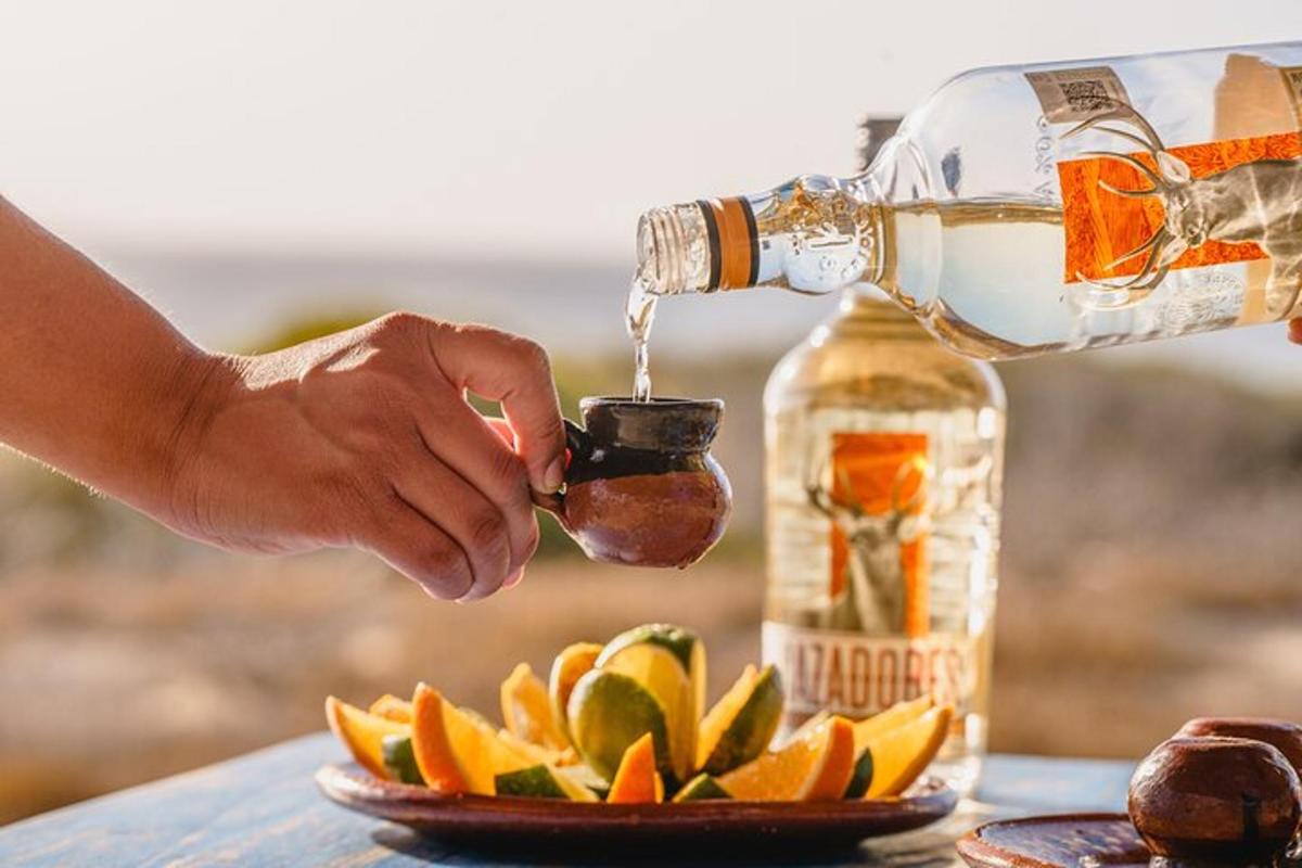 Egy személy egy üveg alkoholt önt egy tányér gyümölcsre
