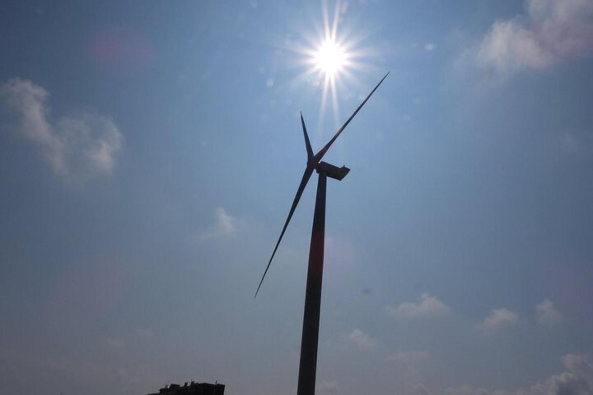 a wind turbine with the sun in the sky