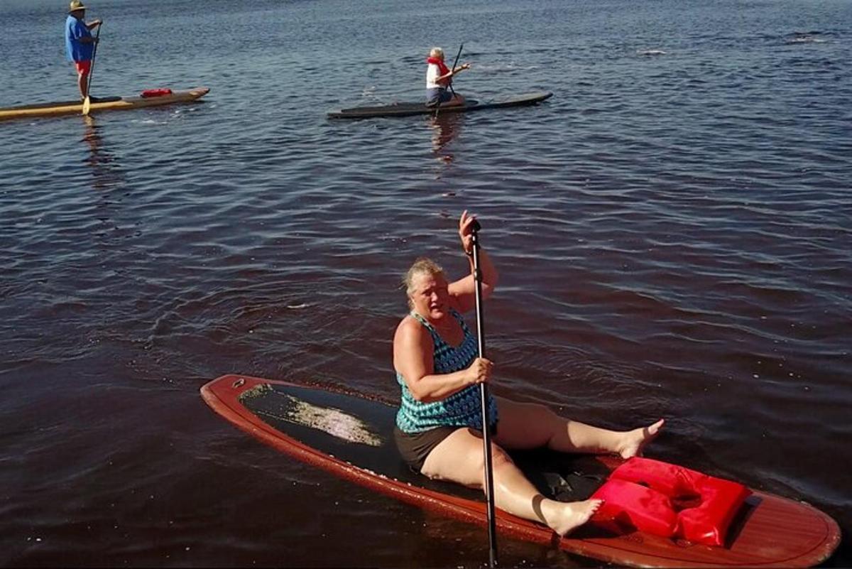 žena sedící na paddleboardu ve vodě