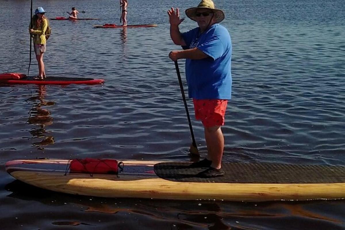 muž stojící na paddleboardu ve vodě