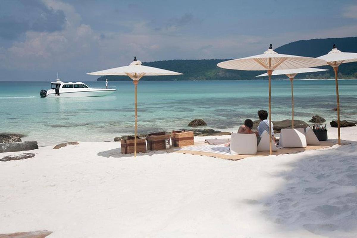 two people sitting under umbrellas on a beach with a boat