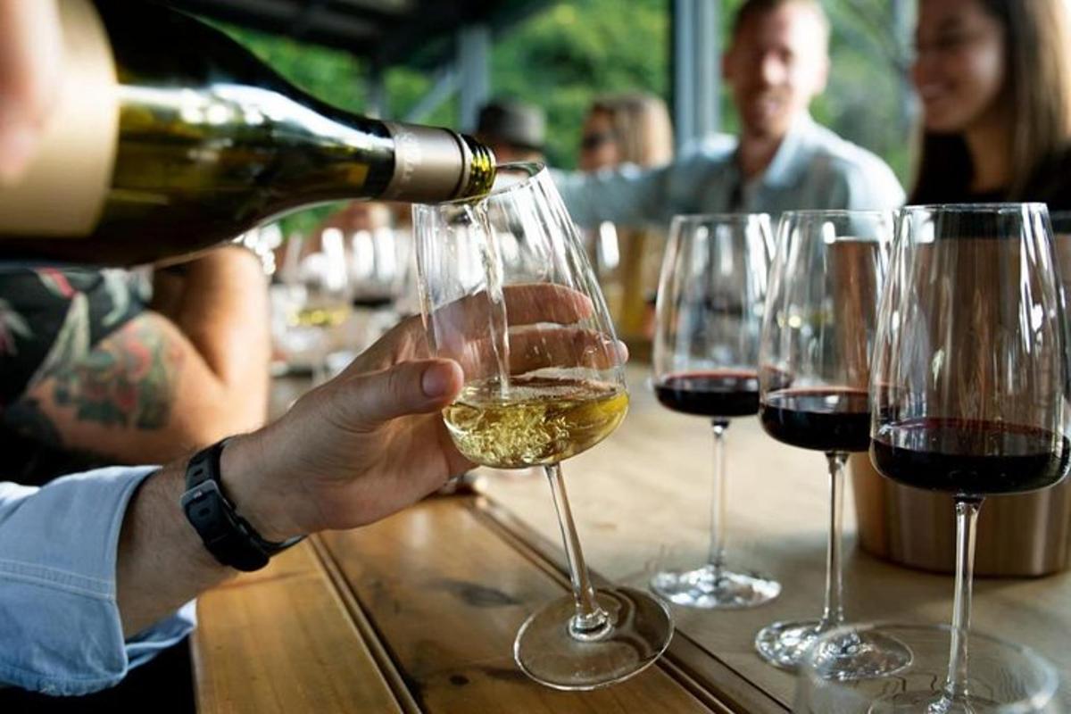 Una persona está sirviendo una copa de vino blanco.