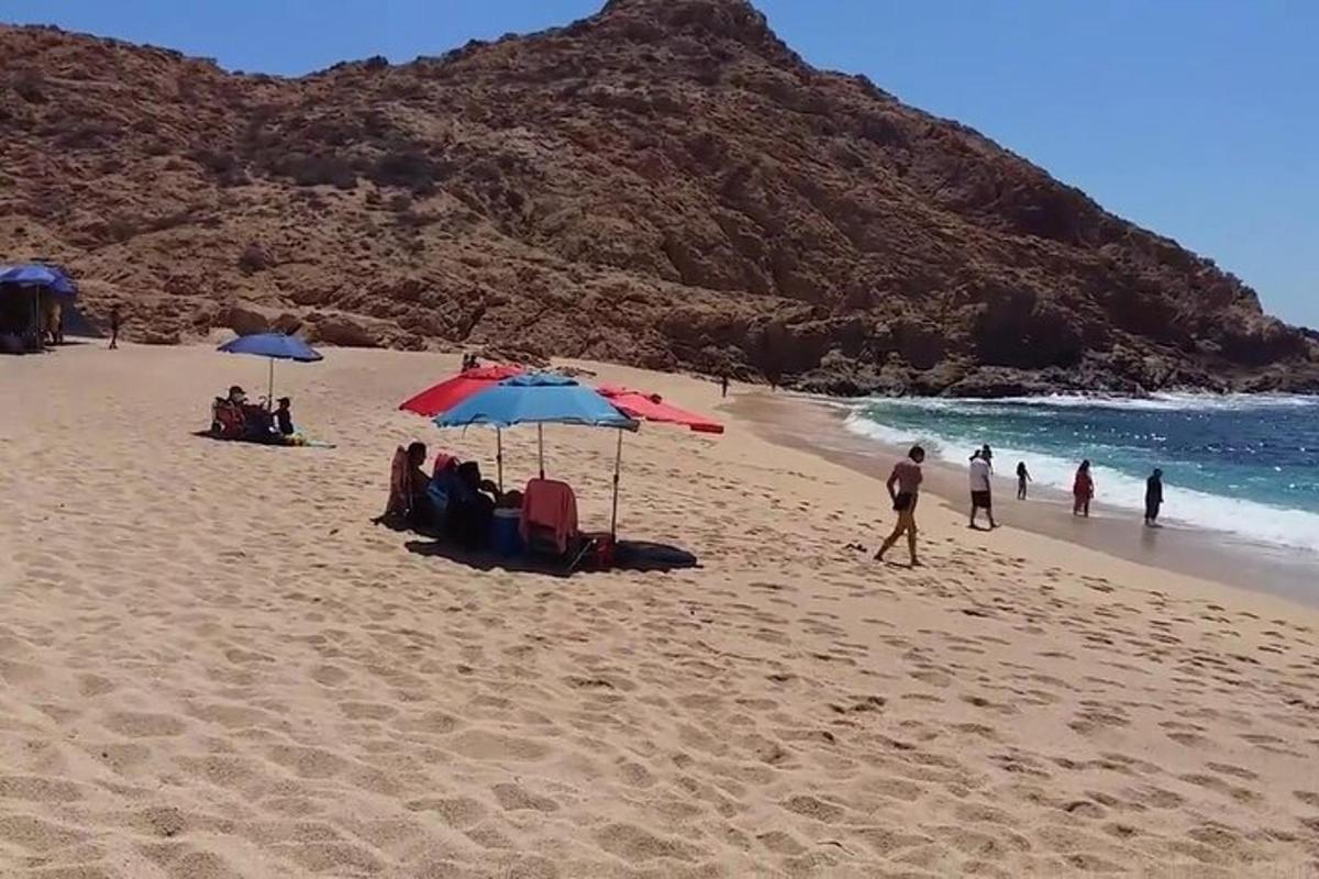sekelompok orang duduk di pantai dengan payung